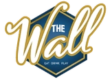 Logo hexagonal avec le texte "THE Wall" en cursive dorée sur fond bleu, accompagné de la mention "Live Game Show"