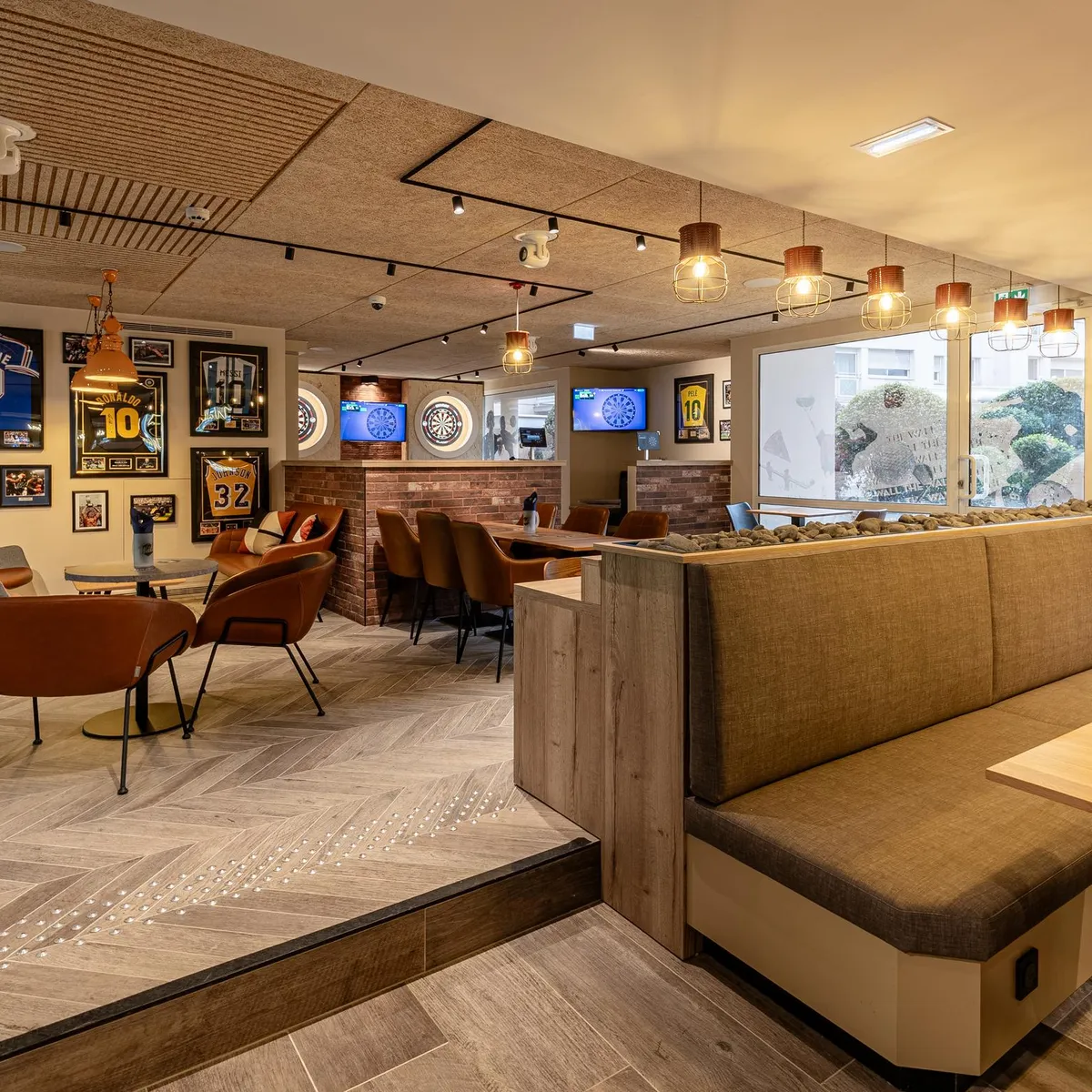 Un intérieur de bar sportif avec des sièges, des tables, des écrans diffusant des matchs et des posters de football sur les murs