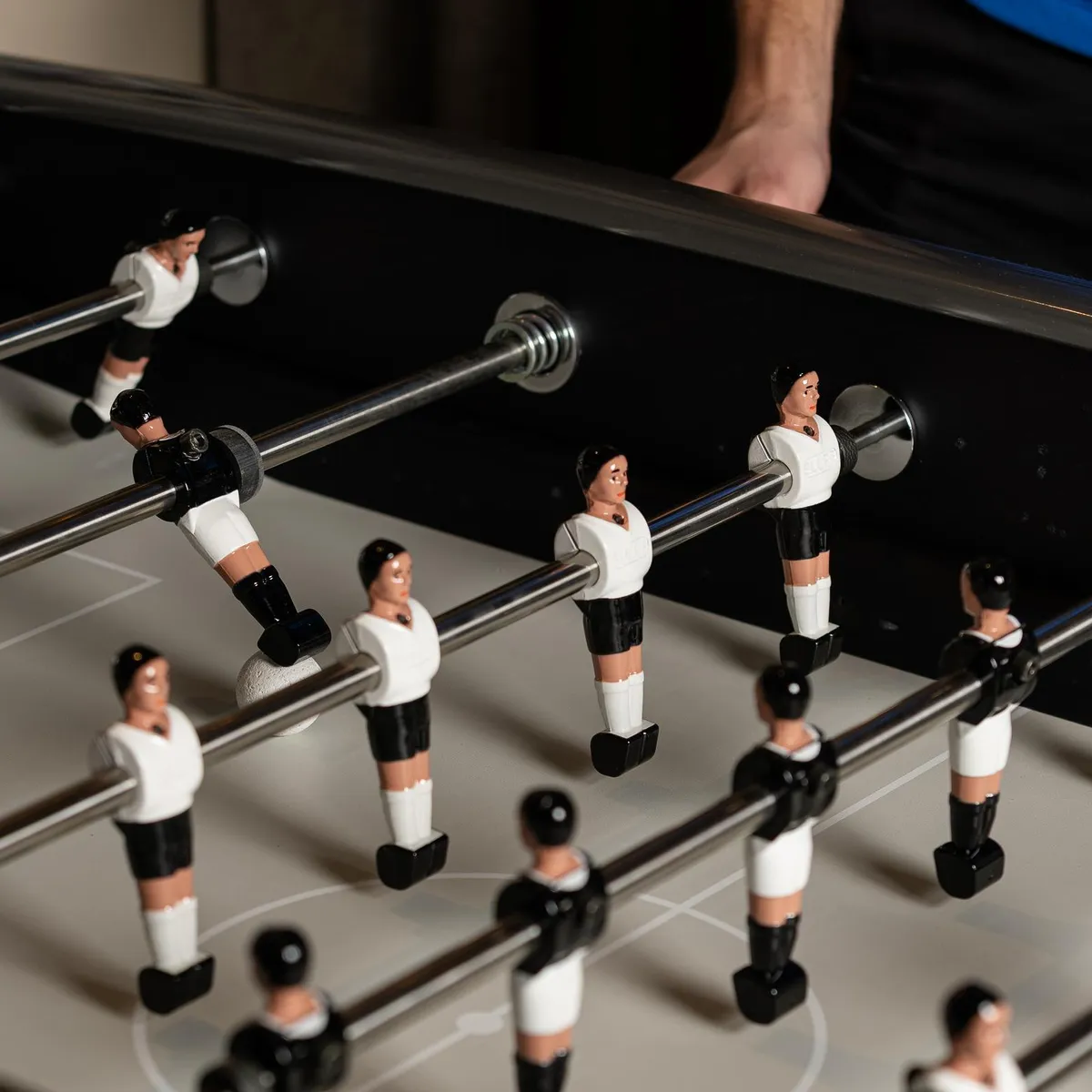 Table de baby-foot avec des figurines de joueurs en plastique positionnées sur les barres métalliques