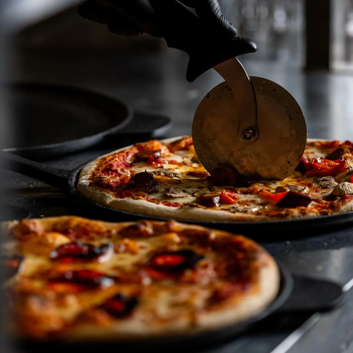 Une pizza est découpée avec une roue à pizza sur une plaque de cuisson
