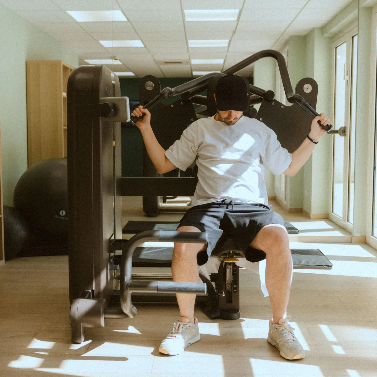 Un homme utilise un appareil de musculation dans une salle de sport bien éclairée