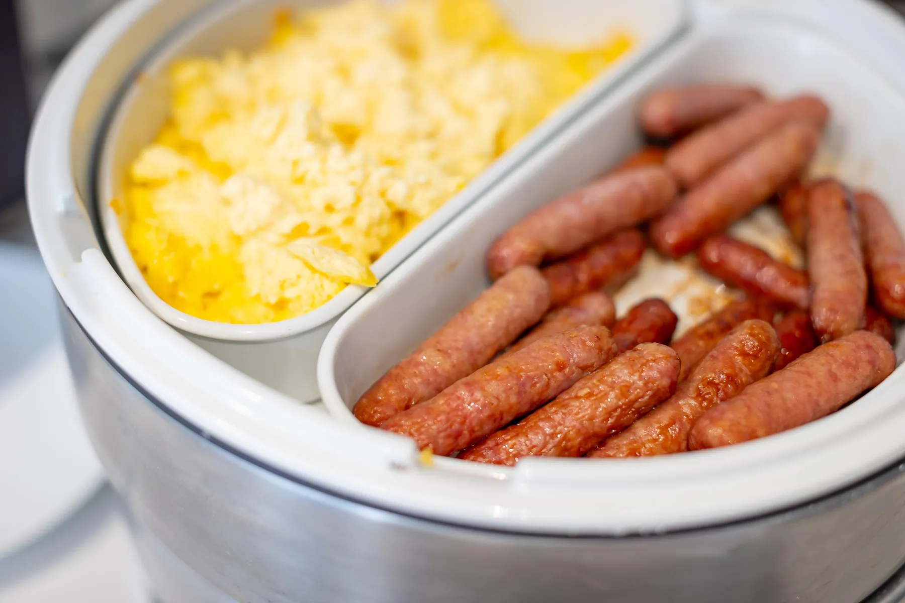 Un plat contenant des saucisses et un bol de fromage râpé