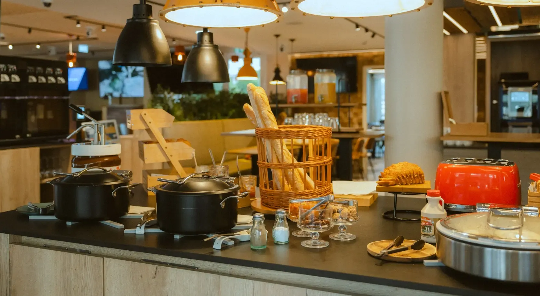 Un buffet de restaurant avec des pots de service, des baguettes dans un panier, des plats de nourriture et des boissons à disposition