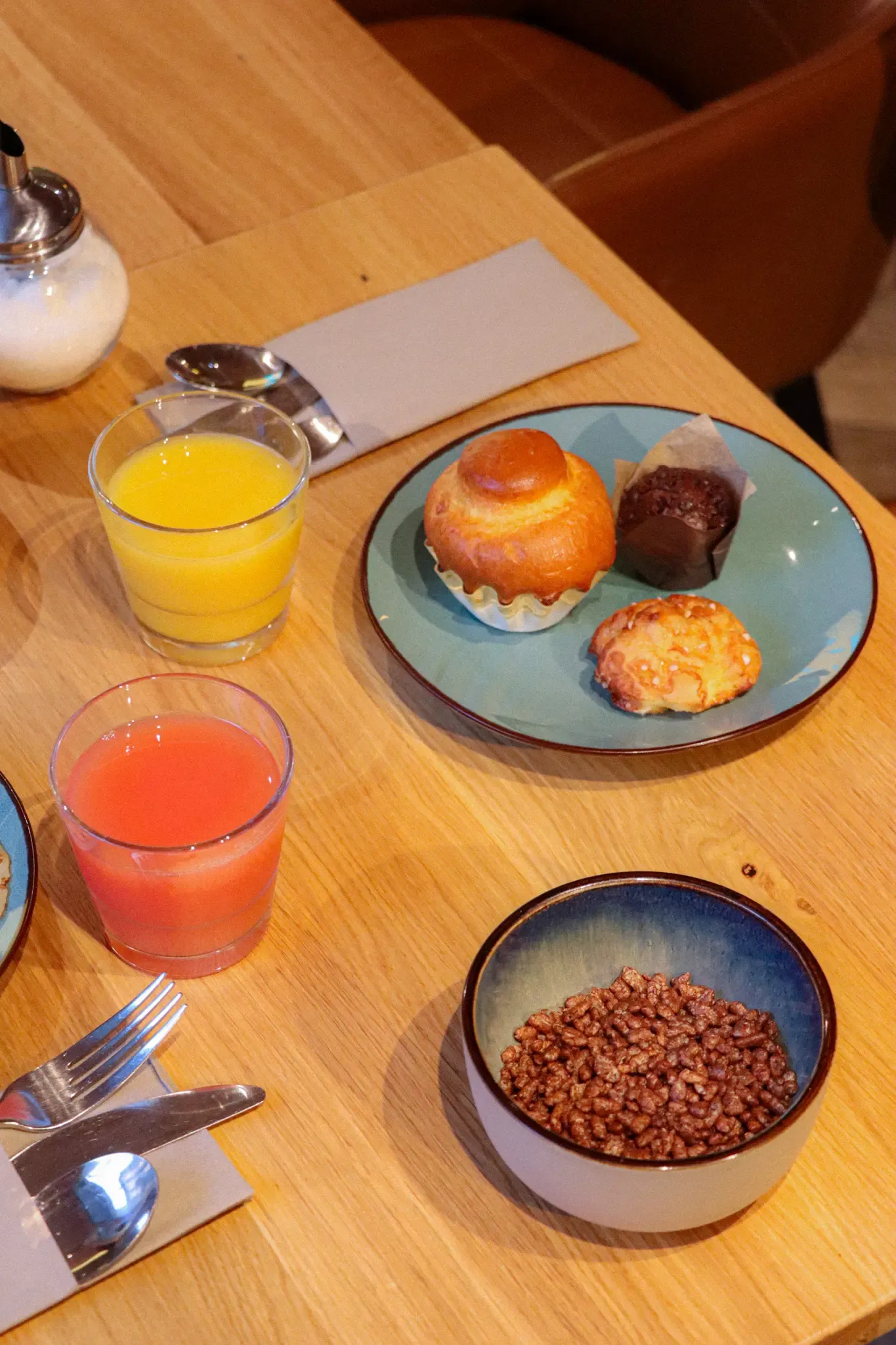 Un plateau avec des boissons, des pâtisseries et un bol de céréales sur une table en bois