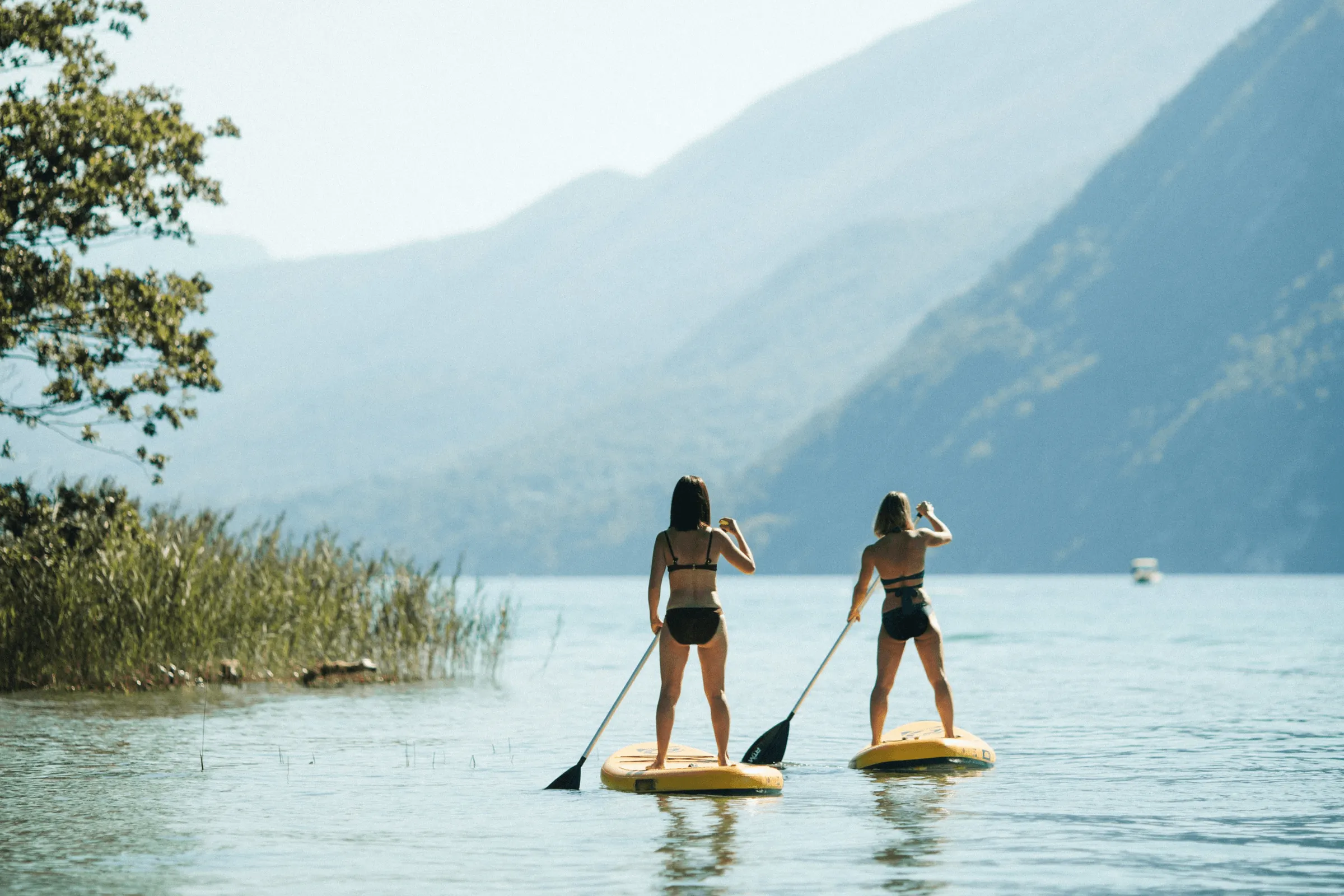 Deux personnes font du paddle sur une étendue d'eau avec des montagnes en arrière-plan