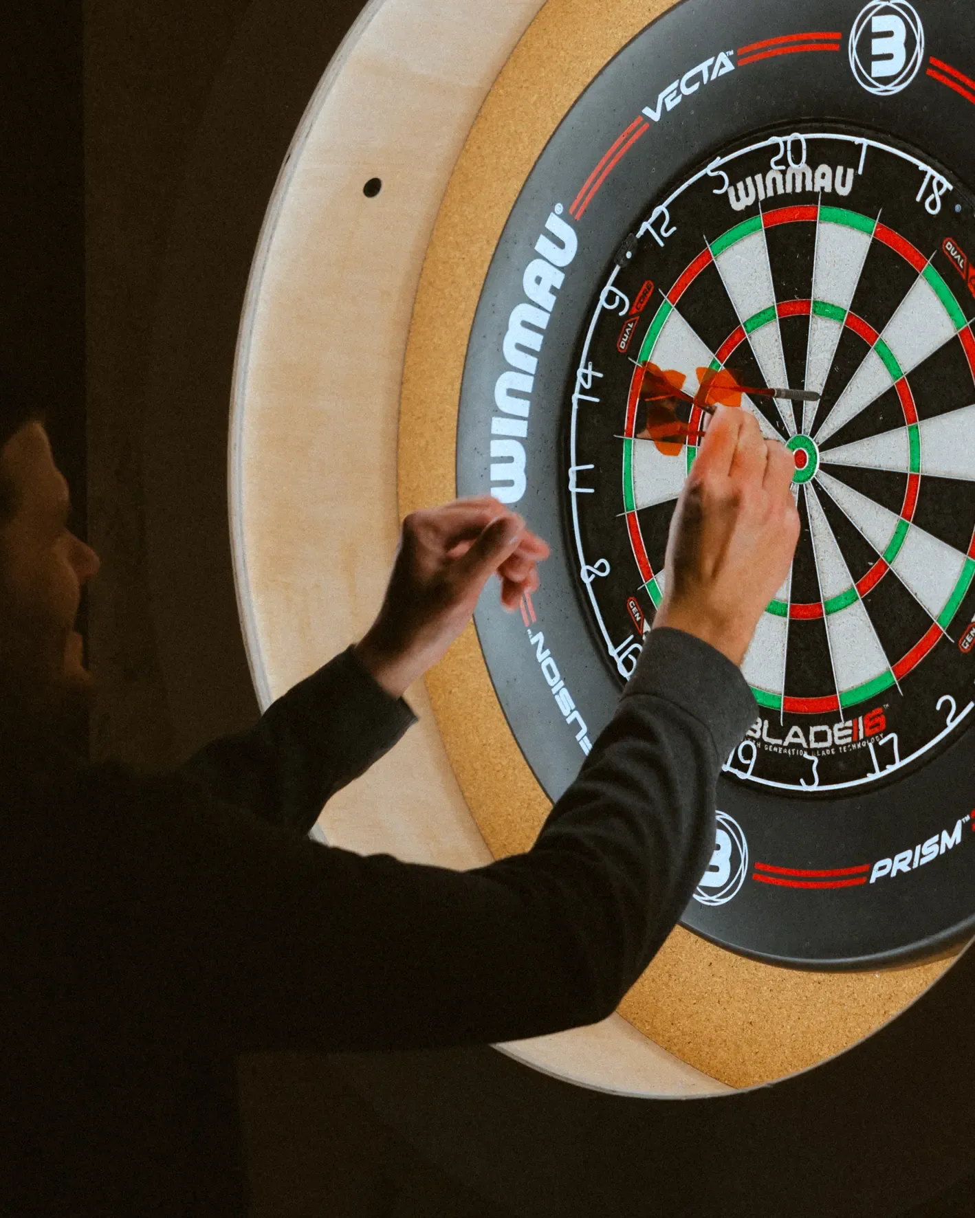 Une personne lance une fléchette vers une cible de jeu de fléchettes