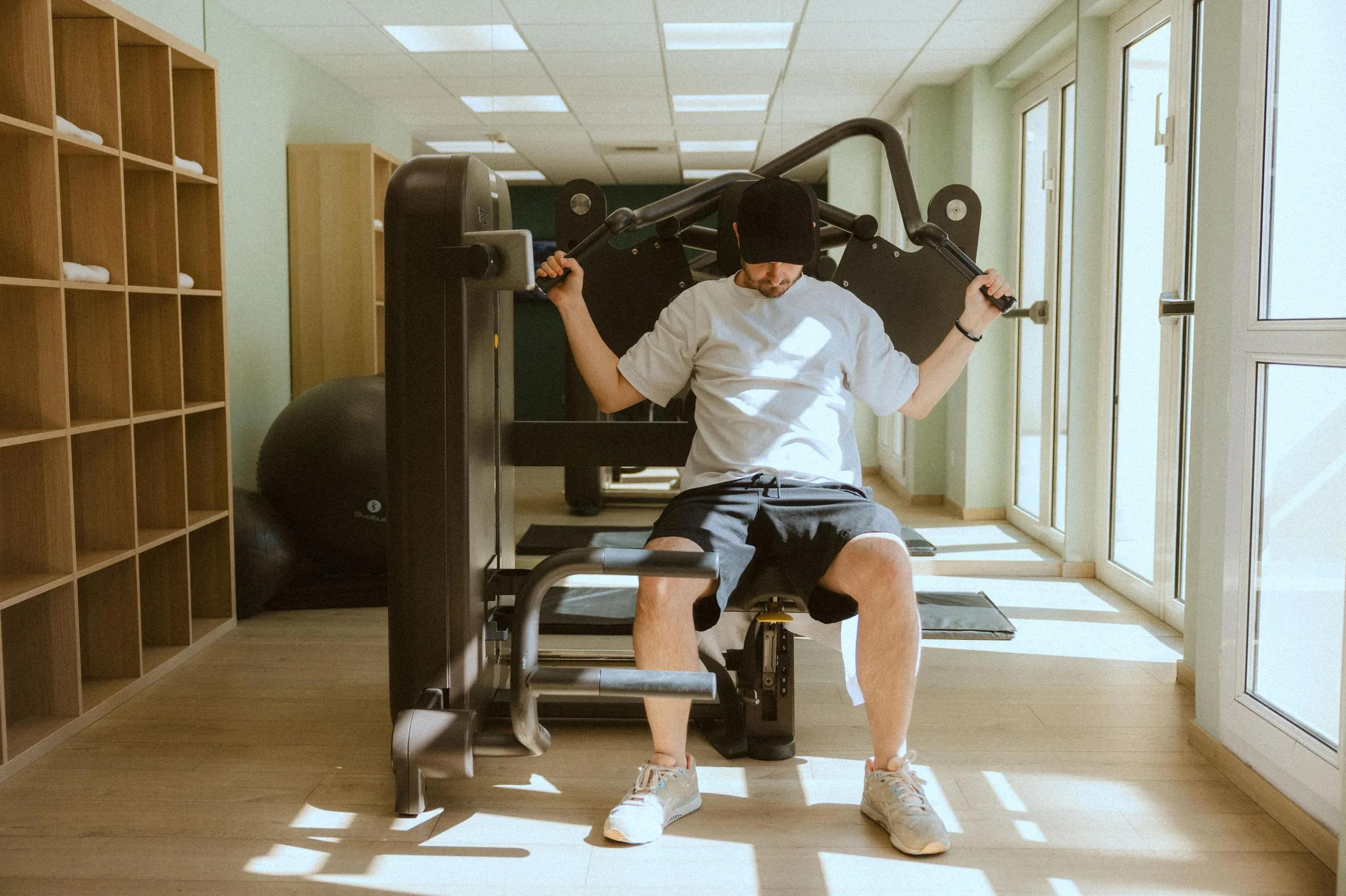 Un homme utilise un appareil de musculation dans une salle de sport bien éclairée