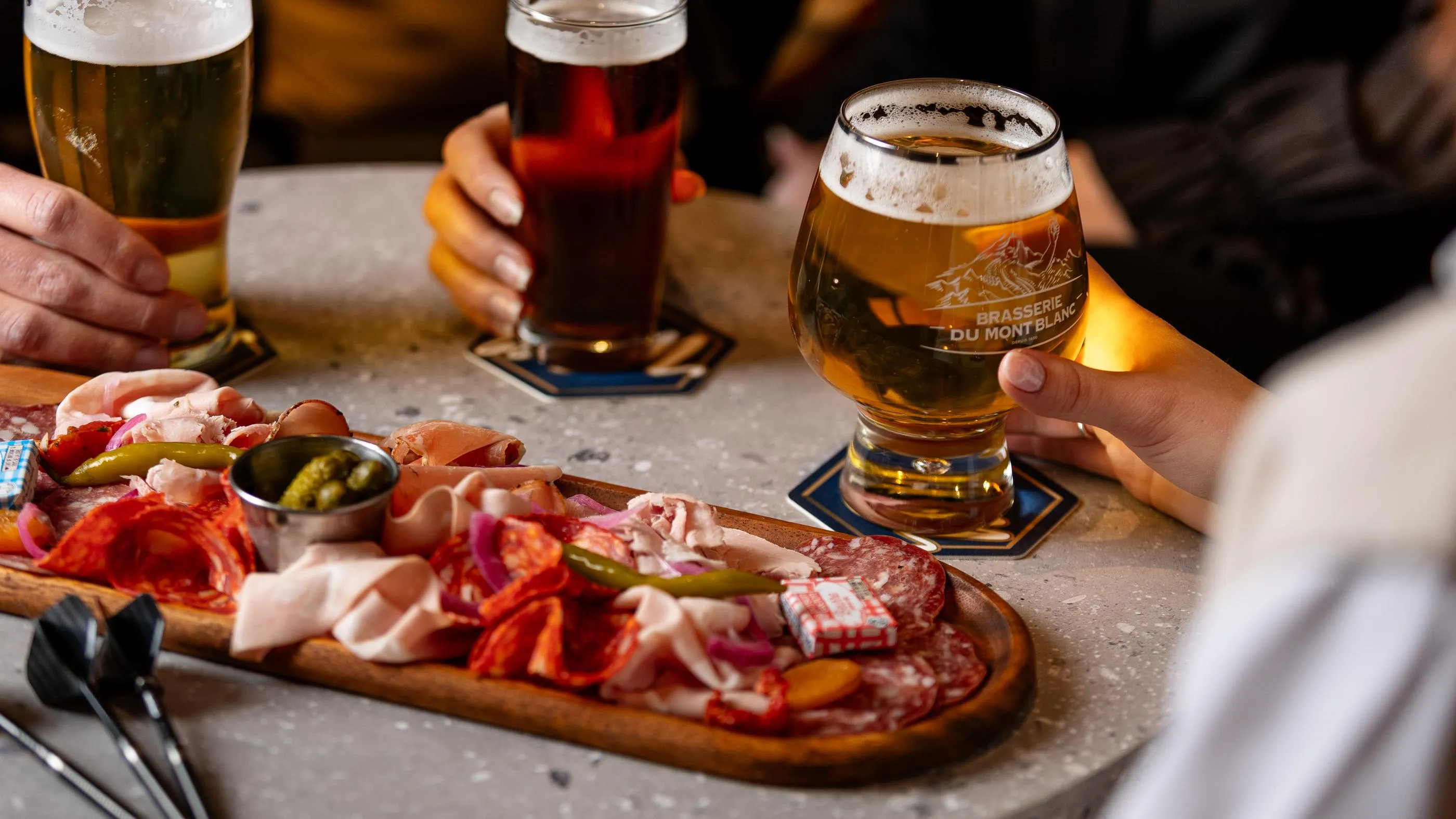 Un plateau de charcuterie et de cornichons avec des verres de bière sur une table